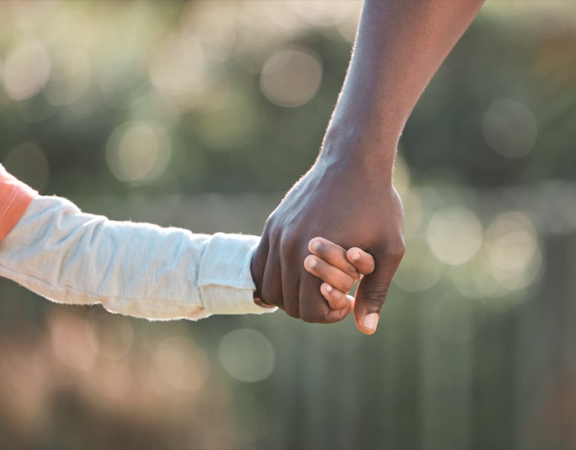 Child and adult holding hands outdoors