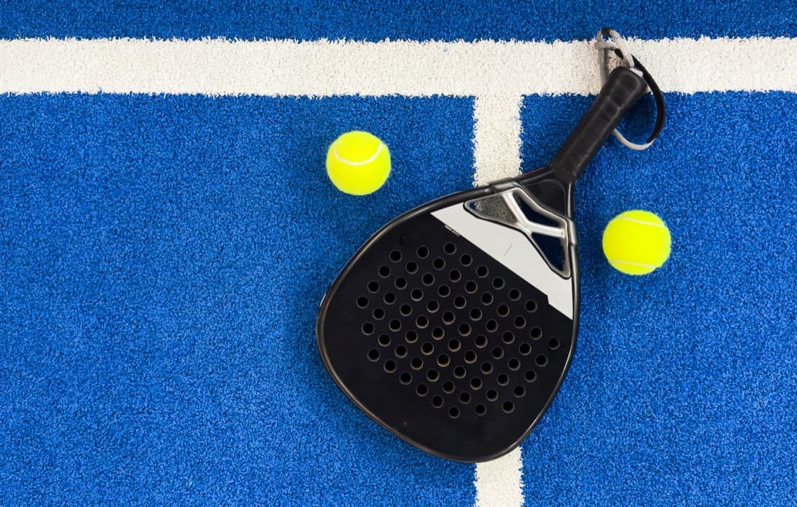 Padel racket and balls on a blue court